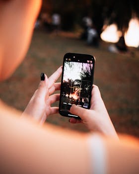 A woman uses a smartphone camera to capture a scenic outdoor moment.