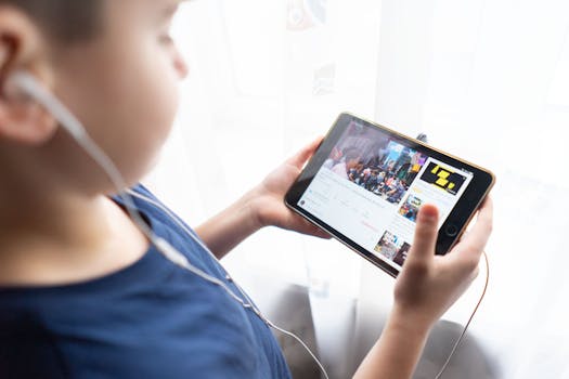 Child holding a tablet indoors, watching videos with headphones, showcasing technology usage by kids.