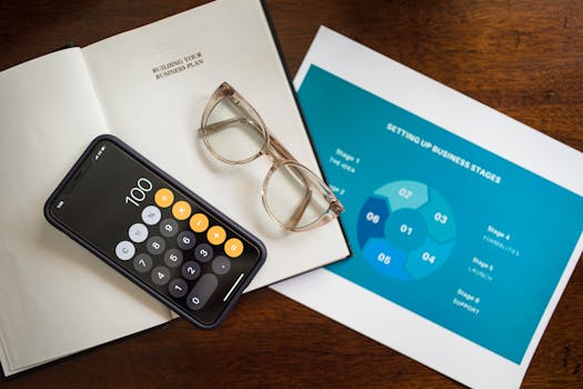 Open notebook, smartphone, and eyeglasses on a desk for business planning.