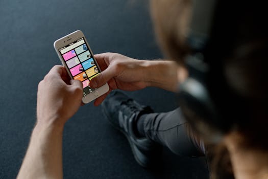 Close-up of a person listening to music on a smartphone while at the gym, focusing on a streaming playlist app.